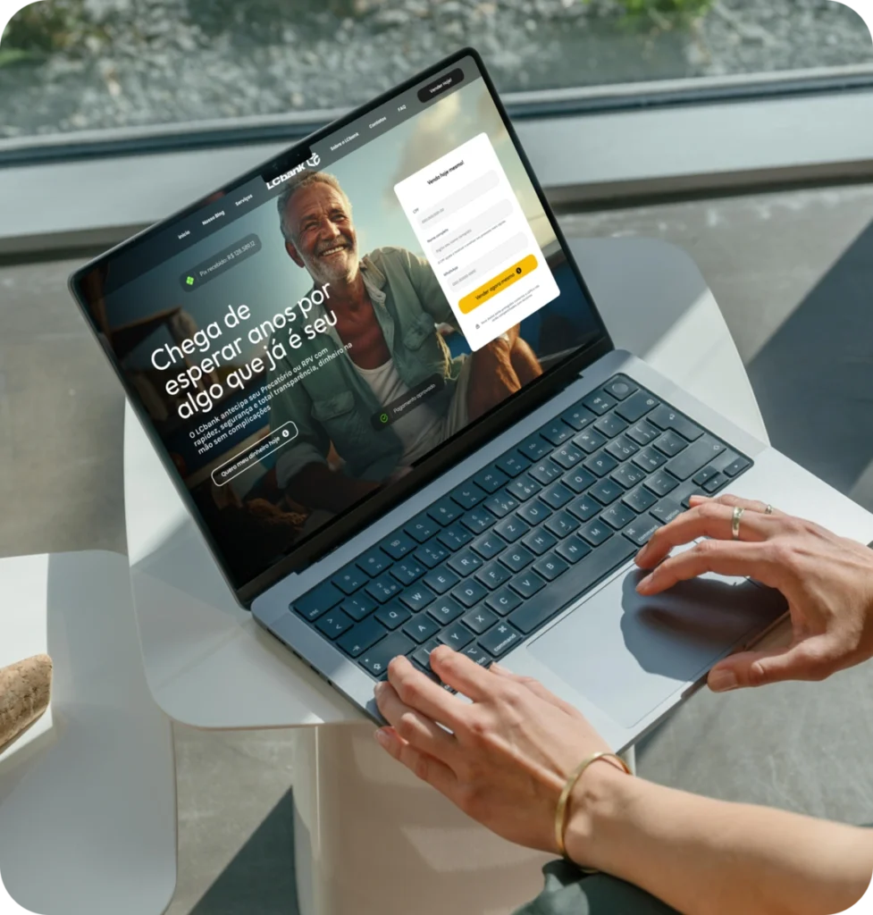 Laptop na mesa exibindo site do LCbank com homem sorrindo